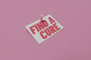 一張粉紅色卡片，上面釘有訊息「Find a Cure」，背景為粉紅色。 — 粉紅色 壁紙