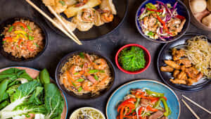 各種亞洲菜餚，包括餃子、麵條和沙拉，排列在深色木桌上。 — 精細 壁紙