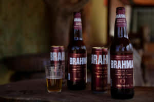 木桌上的 Brahma 啤酒瓶、罐和玻璃杯 — 啤酒 壁紙