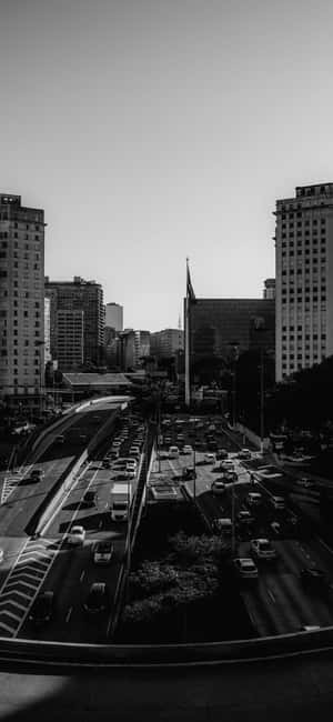 繁忙城市高速公路的黑白景觀，有汽車和高樓大廈。 — Pixel 7 Pro 壁紙