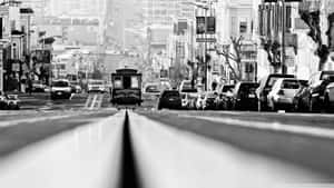 黑白照片顯示一輛纜車正在爬升一條停滿汽車的陡峭城市街道。 — 舊金山 壁紙