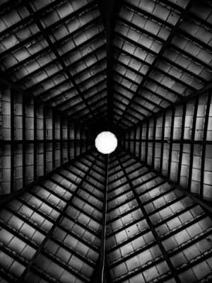 一張對稱工業天花板與中央燈泡的黑白照片。 — 2048x2732 壁紙