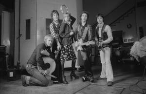 五名身穿1970年代服裝的音樂家在後台手持樂器擺姿勢。 — 翅膀 壁紙