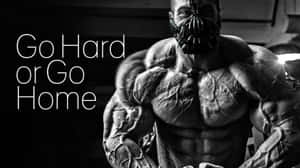 一個肌肉發達的男子戴著蝙蝠面具，旁邊有「Go Hard or Go Home」的文字。 — 激勵 壁紙