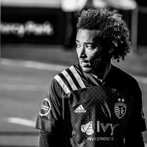 身穿 Sporting Kansas City 球衣的足球運動員，帶著專注的表情望向遠方。 — 釜山 壁紙