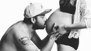 男子在黑白照片中親吻孕婦的肚子。 — 懷孕 壁紙