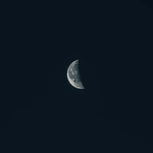 一彎月牙掛在黑暗的夜空中，可見隕石坑。 — 月光 壁紙