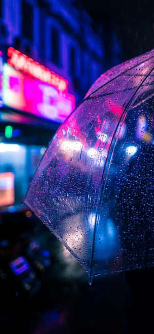 透明雨傘上的雨滴在夜晚城市霓虹燈下閃爍。 — Pixel 11 Pro 壁紙