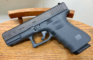 木桌上的黑色Glock 19手槍，帶有可見標記和紋理握把。 — 克拉克 壁紙