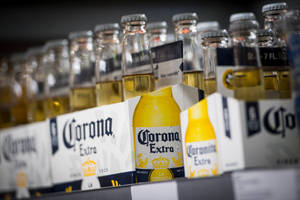 一排 Corona Extra 啤酒瓶和盒子在商店貨架上。 — 啤酒 壁紙