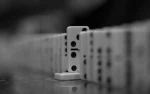 一排多米諾骨牌，其中一塊直立於反光表面。 — 骨牌 壁紙