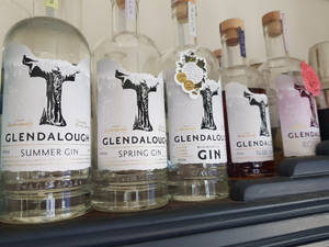 一排帶有季節性標籤的Glendalough琴酒瓶在層架上。 — 品牌 壁紙