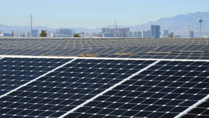 沙漠中的太陽能板，背景是城市天際線。 — 筆電 壁紙