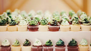 一排排帶有綠色和白色糖霜的杯子蛋糕在層架上。 — 杯子蛋糕 壁紙