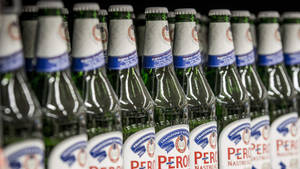 一排排帶有白色和藍色標籤的綠色 Peroni 啤酒瓶。 — 啤酒 壁紙