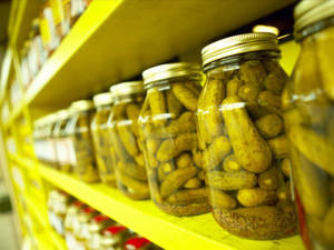 黃色商店貨架上的一排排玻璃罐裝泡菜。 — 醃黃瓜 壁紙
