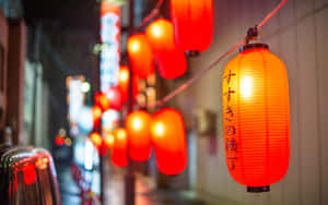 紅色紙燈籠照亮了一條狹窄的城市街道，夜晚伴隨著模糊的霓虹燈。 — 2880x1800 壁紙