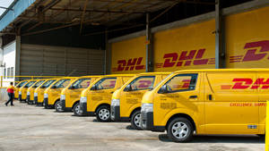 一排黃色DHL送貨貨車停放在倉庫設施。 — Vans 標誌 壁紙