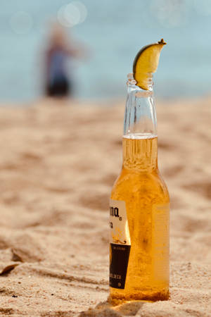 冰涼的Corona啤酒瓶配萊姆角放在沙灘上，靠近海洋。 — 海灘 壁紙