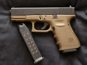 沙色和黑色 Glock 19 手槍連彈匣在深色布料上。 — 克拉克 壁紙