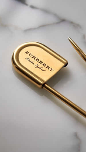 白色大理石背景上的金色 Burberry 鋼筆 — Burberry 壁紙