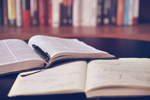 打開的字典和筆記本，筆放在書架附近的桌子上。 — 看書 GIF 壁紙