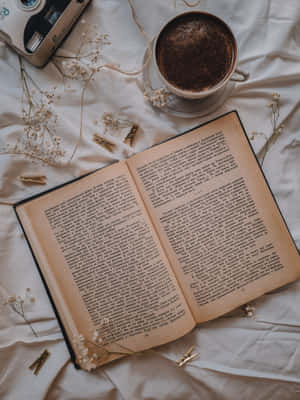 白色床單上打開的書，搭配咖啡和乾燥花。 — 看書 GIF 壁紙