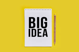 黃色背景上帶有「BIG IDEA」文字和鉛筆的白色筆記本 — 黑色 壁紙