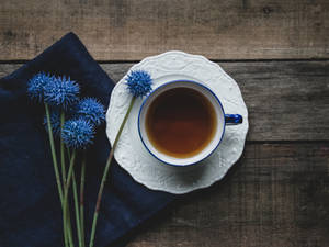 木桌上的一杯茶和藍色花朵。 — 茶園 壁紙