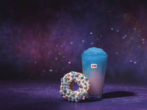 藍色思樂冰和灑糖粒甜甜圈，在紫色閃亮表面上，配星空背景。 — Dunkin Donuts 壁紙