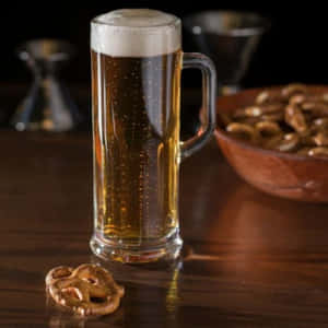 一杯啤酒和一個椒鹽卷餅在木桌上。 — 啤酒 壁紙