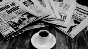木桌上散落的土耳其報紙旁邊，碟子上的一杯咖啡。 — Old Paper 壁紙