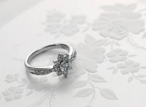 一枚鑽石訂婚戒指放在花卉圖案背景上。 — 結婚戒指 壁紙