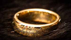 深色紋理皮毛上刻有文字的金戒指。 — Lotr 壁紙