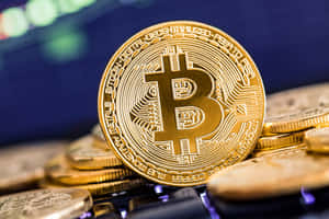 一枚帶有電路圖案的金色比特幣硬幣放在一堆類似硬幣上，靠近發光的螢幕。 — 比特幣 GIF 壁紙