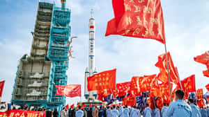 人群在晴朗天空下的火箭發射場揮舞紅旗。 — 唐人街 壁紙