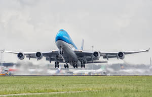 KLM波音747從跑道起飛，背景有草地和雲 — 機場 壁紙