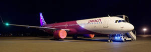 Peach Airlines飛機夜間停泊在停機坪上，燈光閃耀 — 伸展台 壁紙