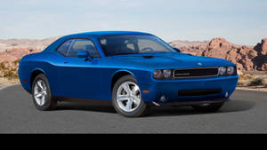藍色 Dodge Challenger 肌肉車在沙漠公路上，背景有紅色岩石地貌。 — 山脈 壁紙