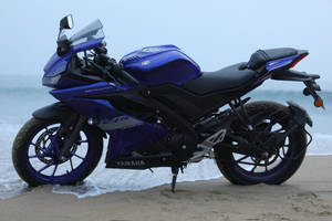 藍色Yamaha R15機車停放在海灘上，伴隨海浪 — 改裝摩托車 壁紙