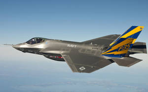 F-35戰鬥機帶有藍色和黃色尾翼標誌飛越地球。 — 航太 壁紙