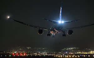 夜間在城市上空降落的飛機，燈光閃爍。 — 航太 壁紙