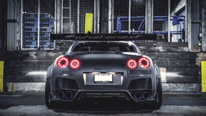 訂製灰色日產GT-R，紅色尾燈，停放在工業車庫。