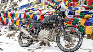 黑色機車停泊在雪中，旁邊是山上的彩色經幡。 — 腳踏車 GIF 壁紙