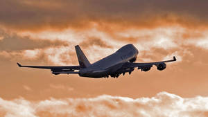 貨運飛機在橙色日落雲彩前飛行。 — 夕陽天空 壁紙