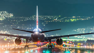 夜間濕滑跑道上的飛機，背景有城市燈光。