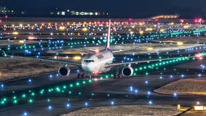 一架大型飛機在夜間於燈火通明的跑道上滑行。 — 伸展台 壁紙