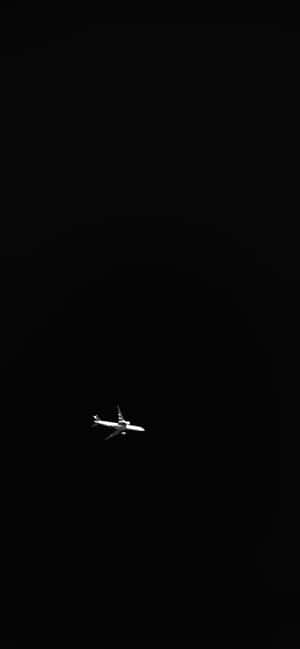 一架飛機獨自在黑色夜空中飛行。 — Galaxy A16 壁紙