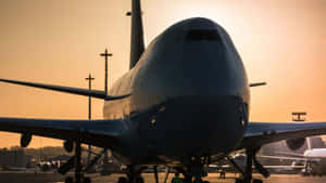 大型飛機在日落時停放在機場停機坪上，溫暖的橙色天空。 — 溫暖 壁紙