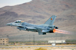 灰色戰鬥機在沙漠地形上空起飛時點燃後燃器。 — 空軍 壁紙